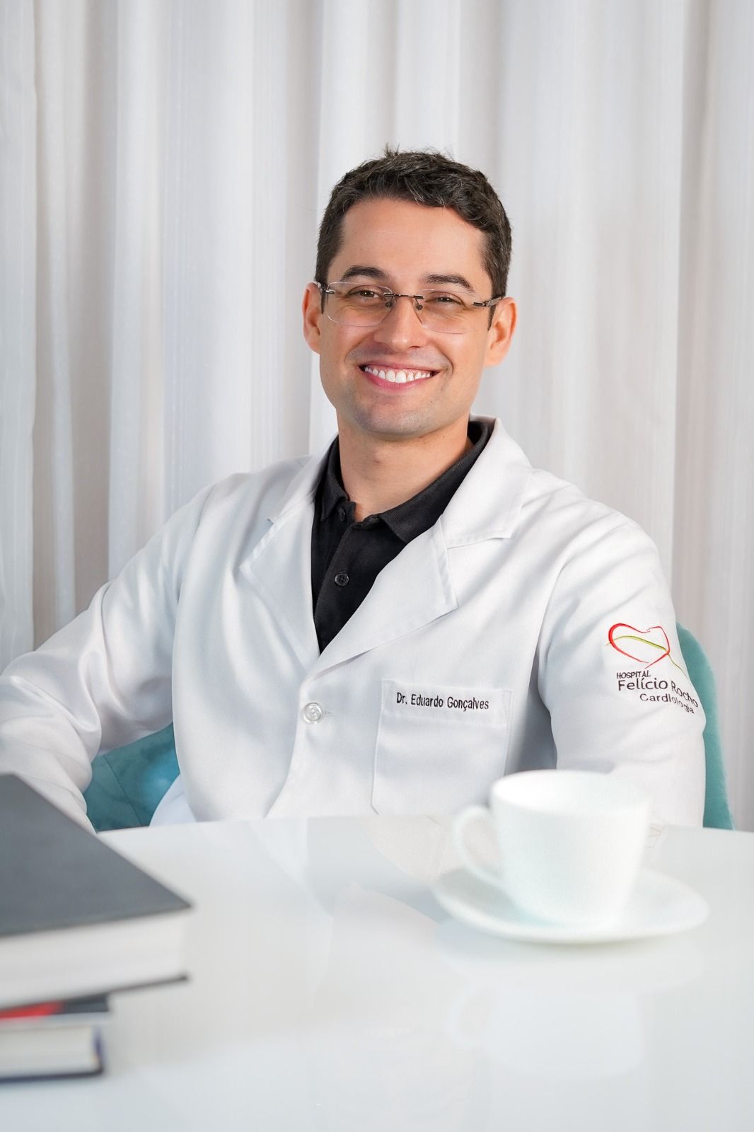 Dr. Eduardo Gonçalves de jaleco branco no consultório